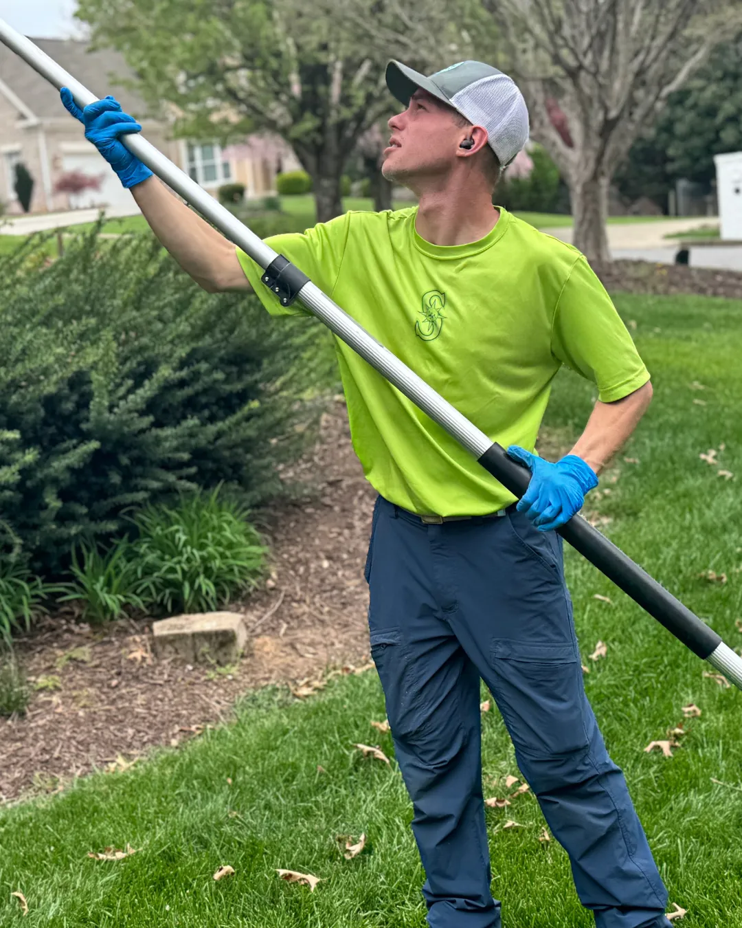 shield pest technician reaching up to grab a spiders web